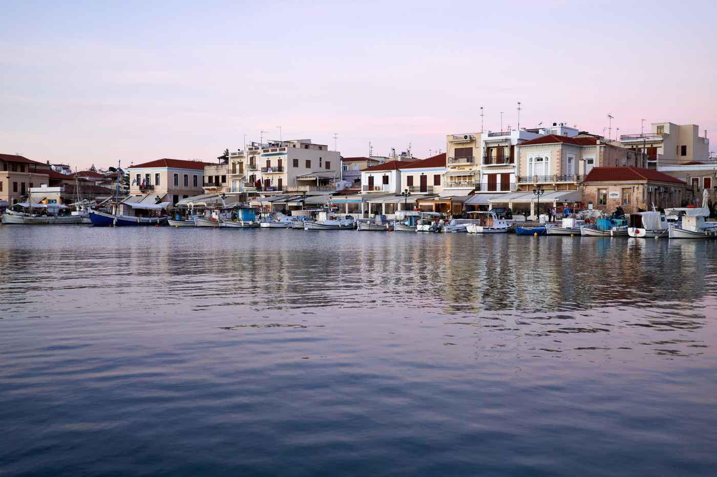 The harbourfront tavernas and bars of Aegina Town lit up in the evening