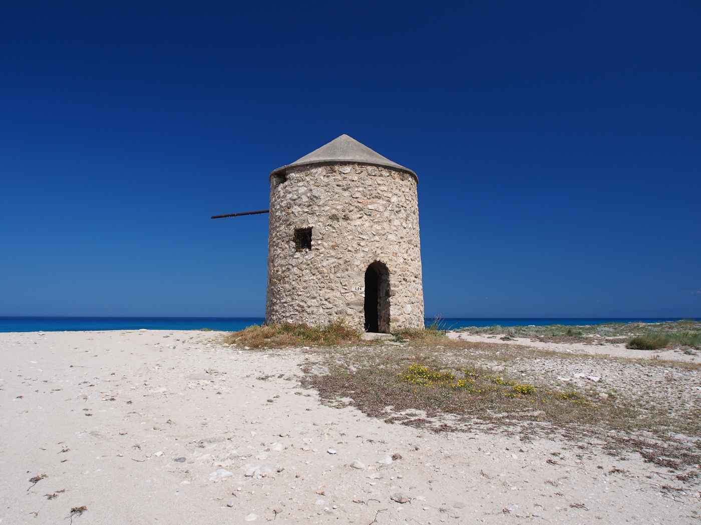 Gyra beach windmill on the sand above the deep-blue sea, Lefkada