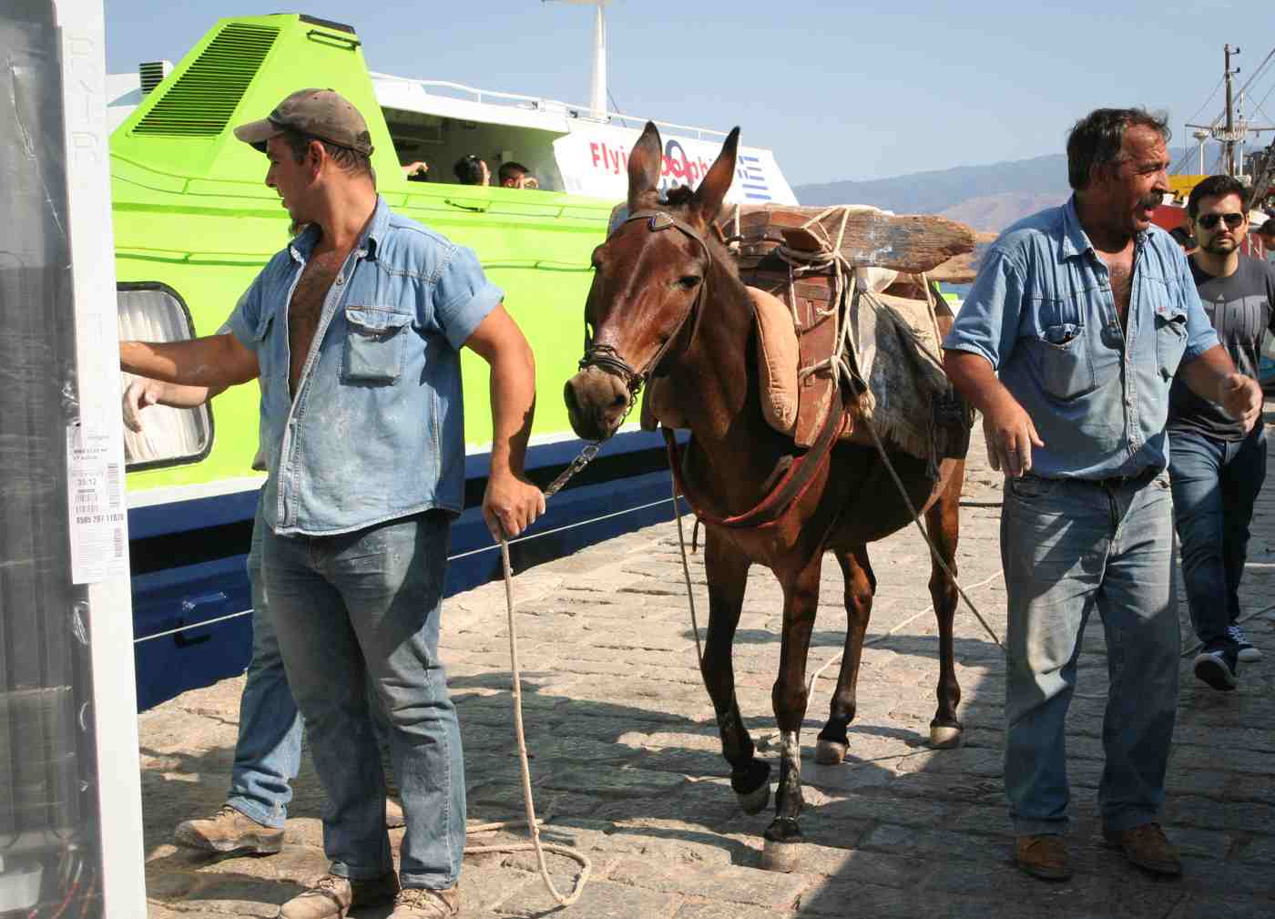 Hydra donkeys: a muleteer leading a laden mule along the harbour quay by the ferry
