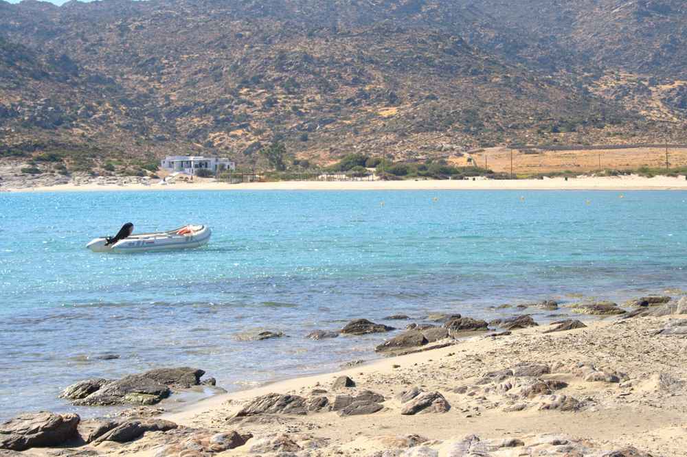 A boat moored in the turquoise bay of Manganari, a highlight of Ios boat trips