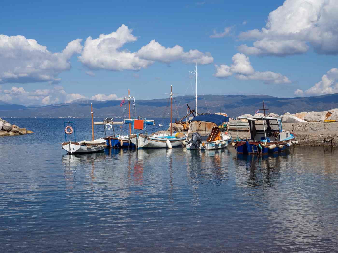 Traditional fishing boats moored in Kamini harbour on Hydra, with the Peloponnese beyond