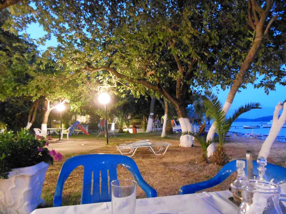 An evening taverna terrace lit at dusk by the sea on Lefkada