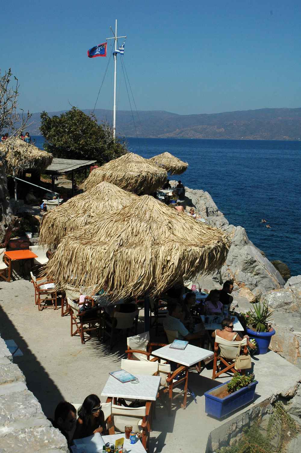 The cliff-side Spilia cafe on Hydra, its thatched umbrellas above the swimming spot and sea
