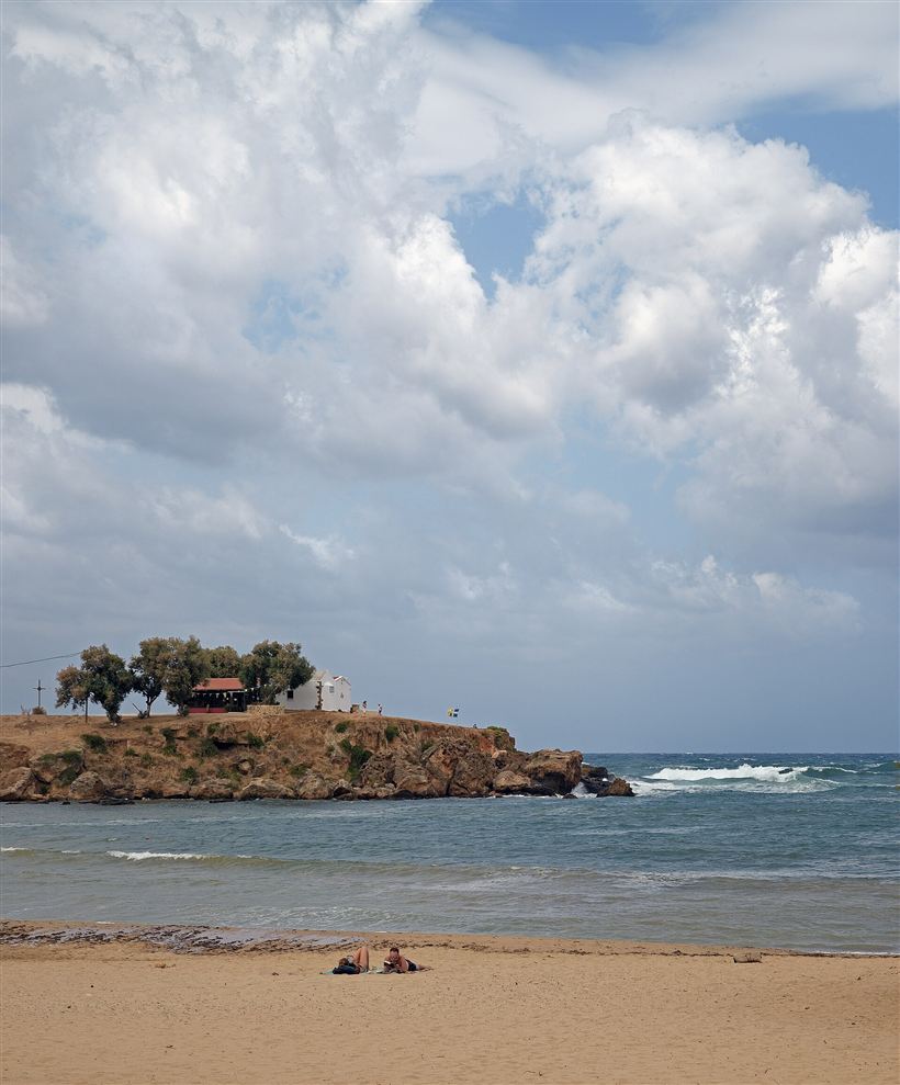 Iguana Beach at Agioi Apostoli near Chania, a sheltered sandy cove below the pine-topped chapel headland