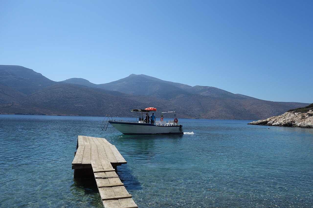 The shuttle boat on the brilliantly clear turquoise water off the islet of Nikouria, northern Amorgos