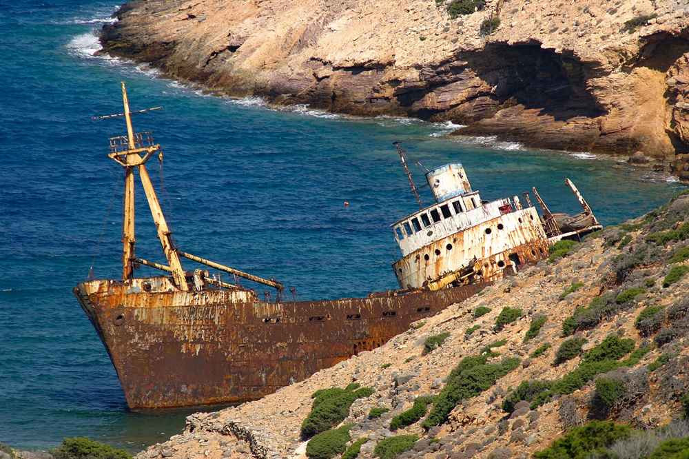 The rusting orange hull of the Olympia shipwreck run aground in its cove near Kalotaritissa, southern Amorgos