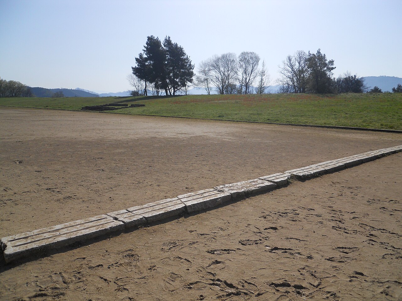 The Ancient Stadium of Olympia seen along its length, the grass banks rising on either side