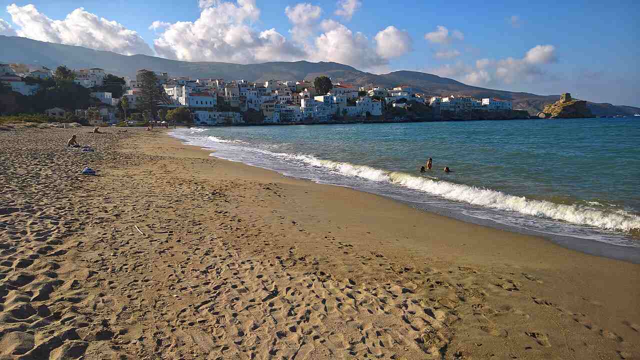 The town beach of Chora, Andros, with the capital and the Tourlitis rock beyond