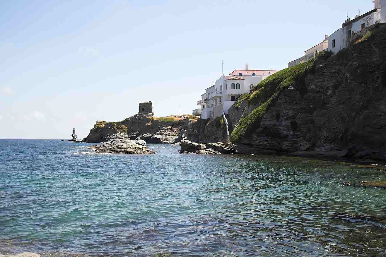 The seafront of Chora, Andros, with the ruined Venetian castle and the Tourlitis lighthouse beyond