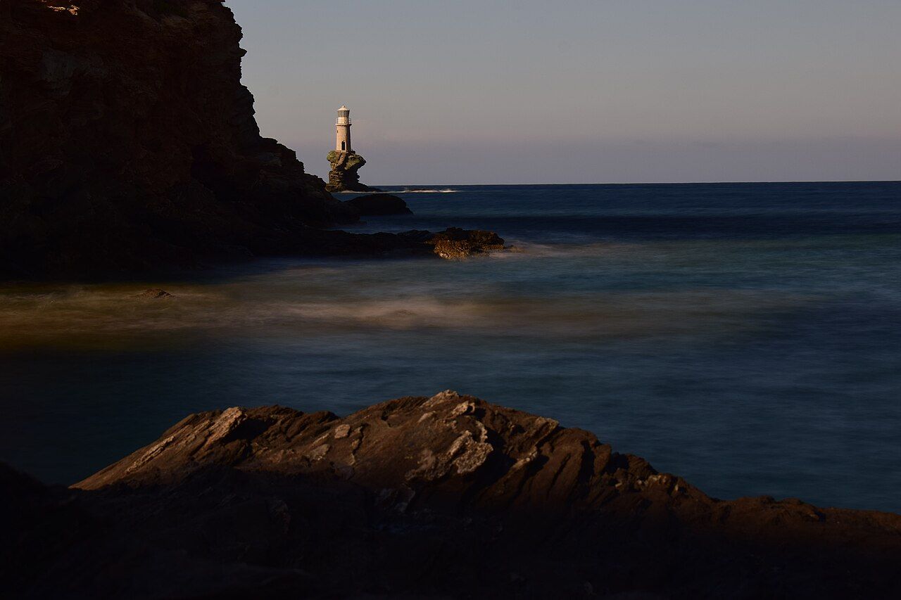 The white tower of Tourlitis lit by the low golden light of evening below the castle of Chora, Andros