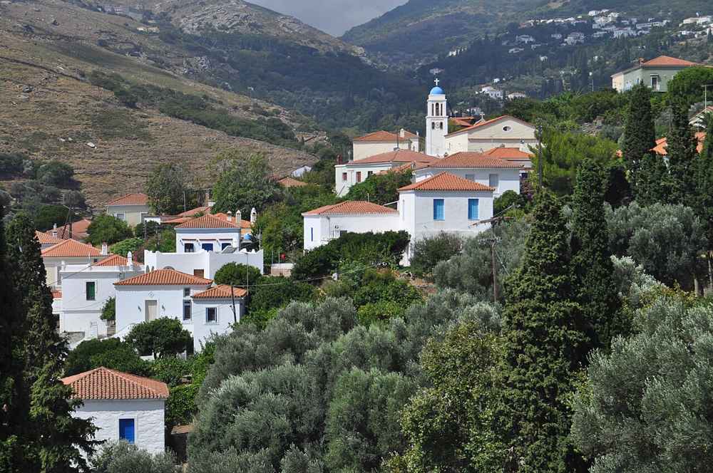 The green village of Stenies with its whitewashed houses and blue-domed church on the slopes of Andros