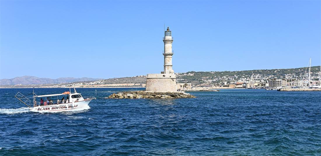 A glass-bottom tour boat passing the Egyptian lighthouse at the Chania harbour