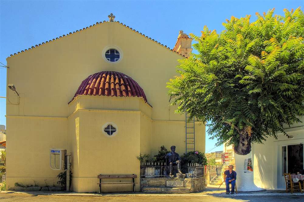 A church and war-memorial statue in the village square of Anogia on the slopes of Mount Psiloritis