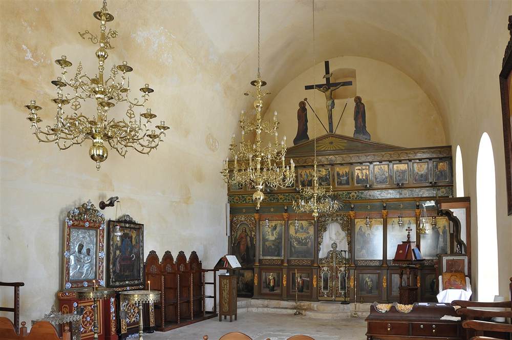 The gilded iconostasis and chandeliers inside the church of the Chrysoskalitissa Monastery in Crete