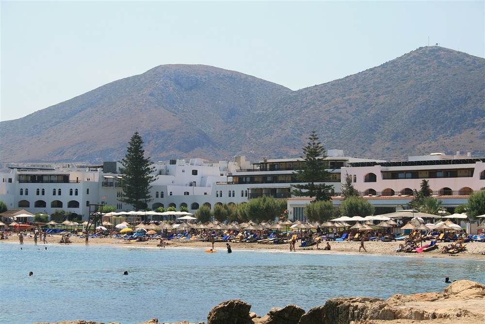 The resort beach at Hersonissos, Crete, with its sunbeds and hotels below the hills