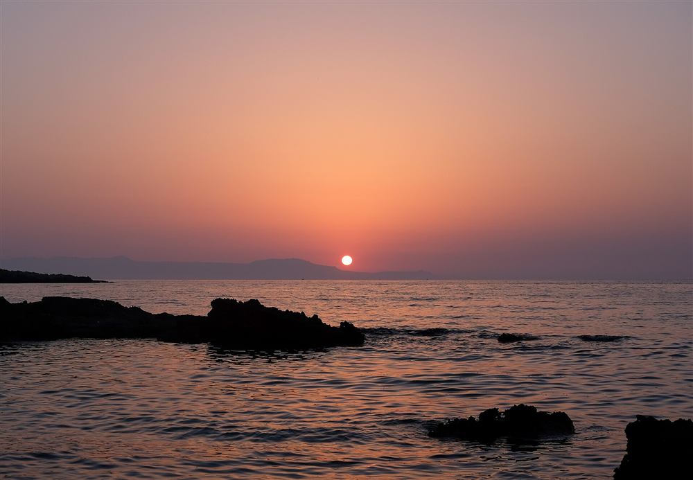 The calm sea and rocky islet of Kalathas on the Akrotiri peninsula near Chania at dusk, Crete