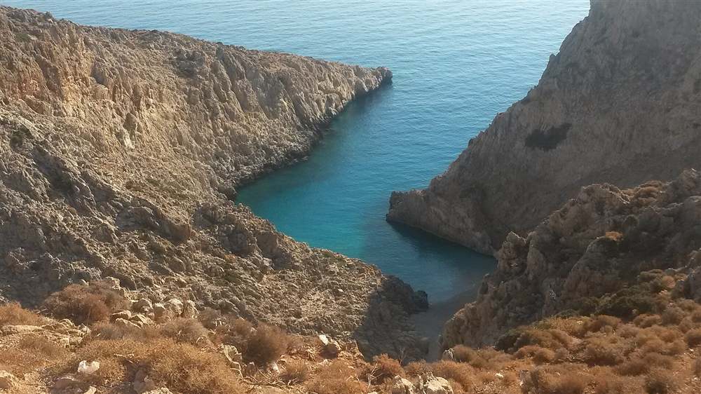 The deep turquoise water of the Seitan Limania inlet cutting between rocky cliffs near Chania, Crete