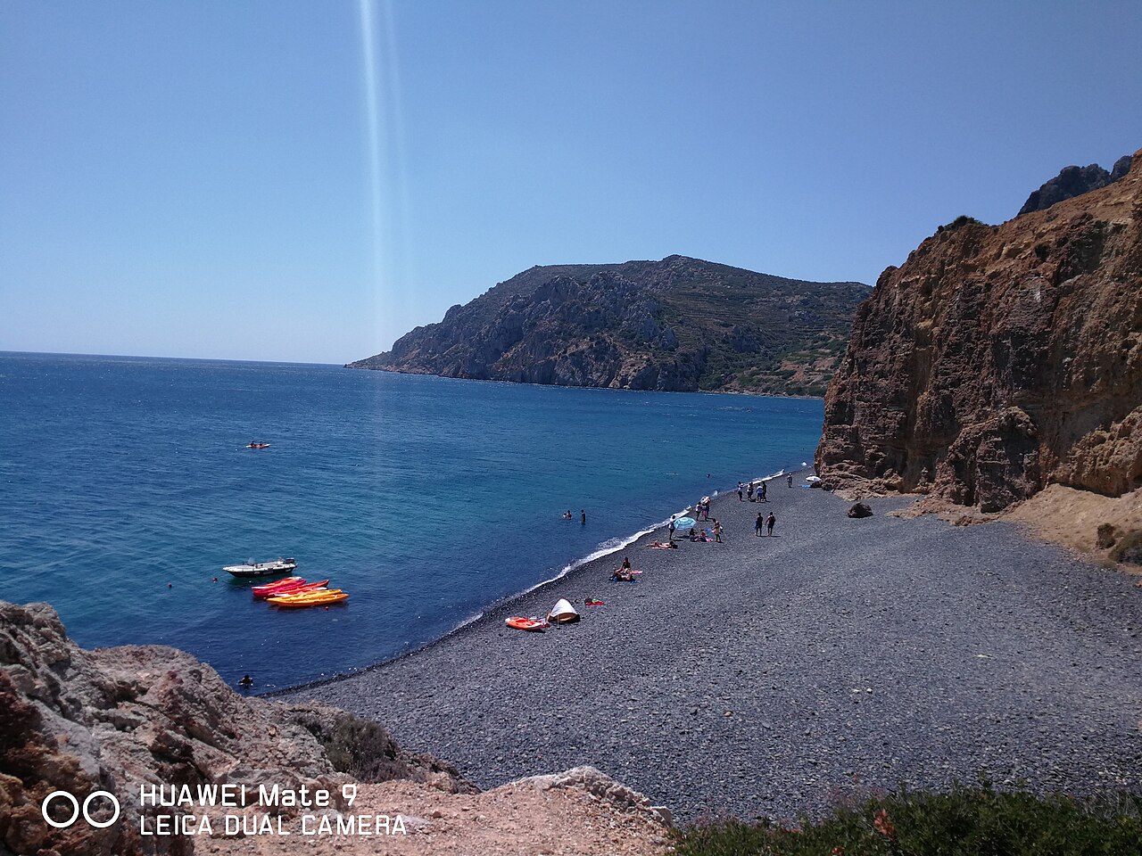 The black volcanic pebbles and deep blue water of Mavra Volia beach in Chios