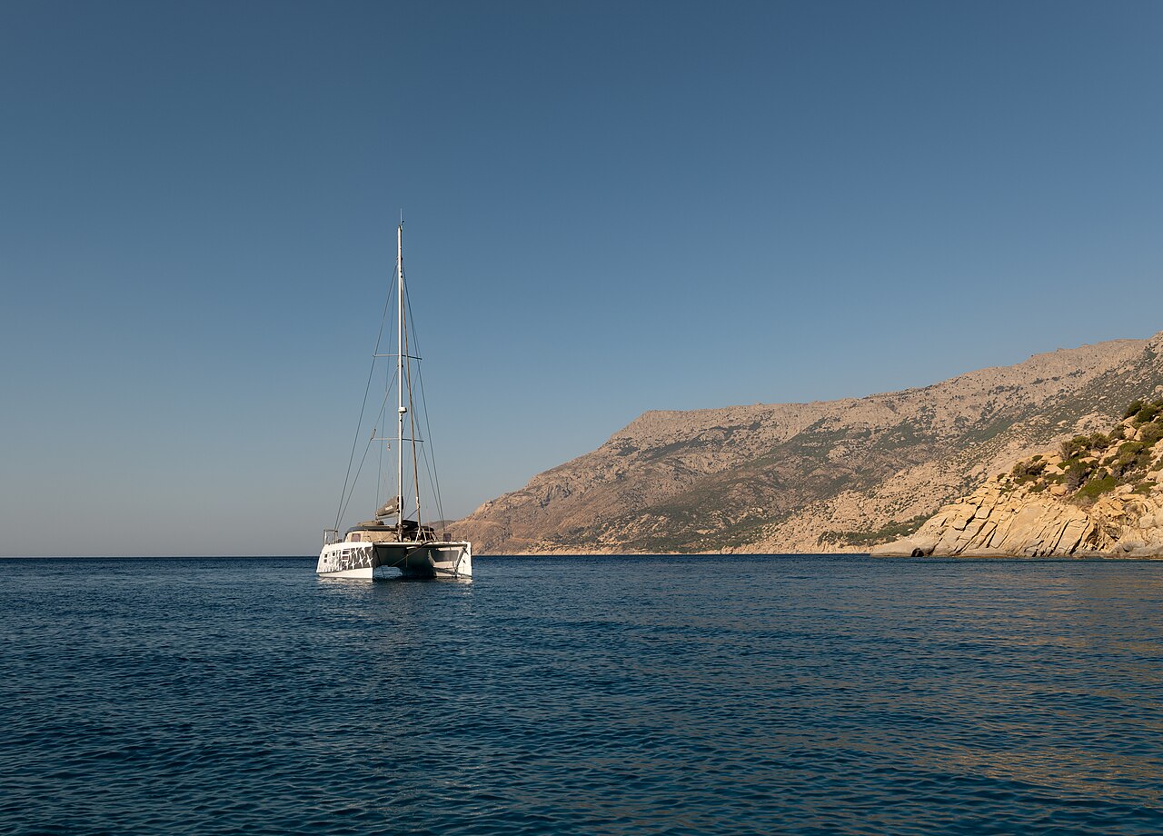 A sailing catamaran anchored in the clear turquoise water of the Aegean, the style of a Chios sailing cruise