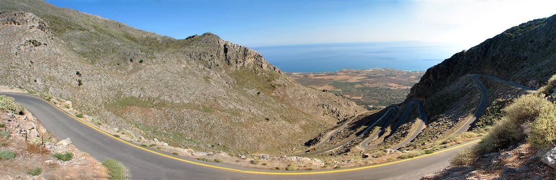 A hairpin mountain road winding down to the sea in west Crete, ideal for a Chania hire car