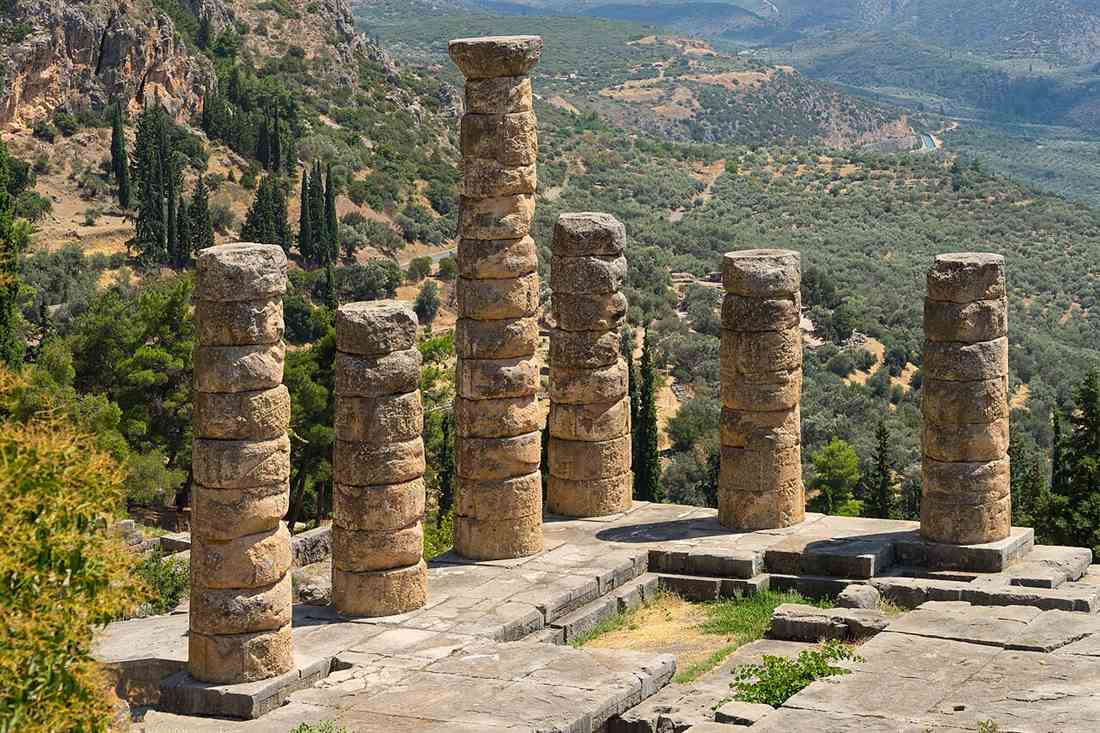 The six Doric columns of the Temple of Apollo at Delphi above the olive valley toward the Gulf of Corinth