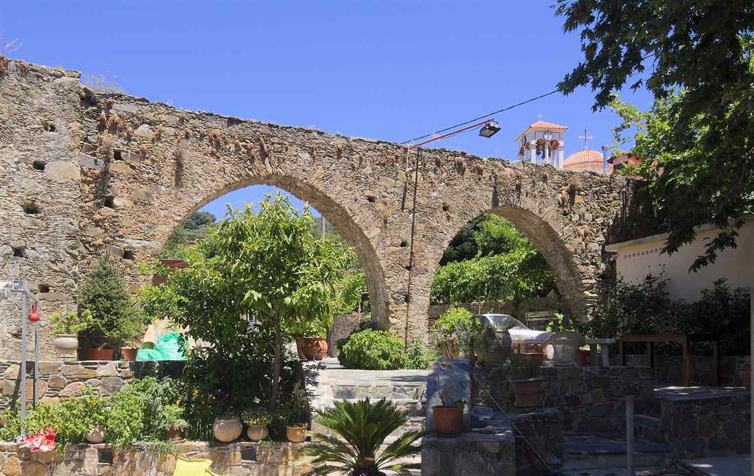 The old stone aqueduct and church of the chestnut village of Elos in west Crete