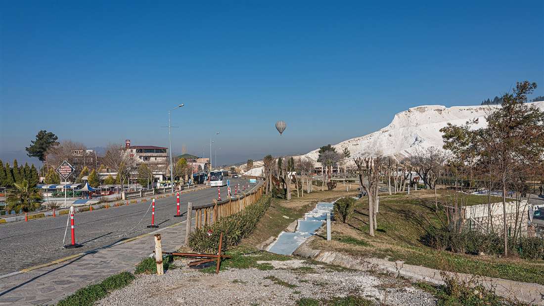 A hot air balloon aloft over the white travertine terraces of Pamukkale