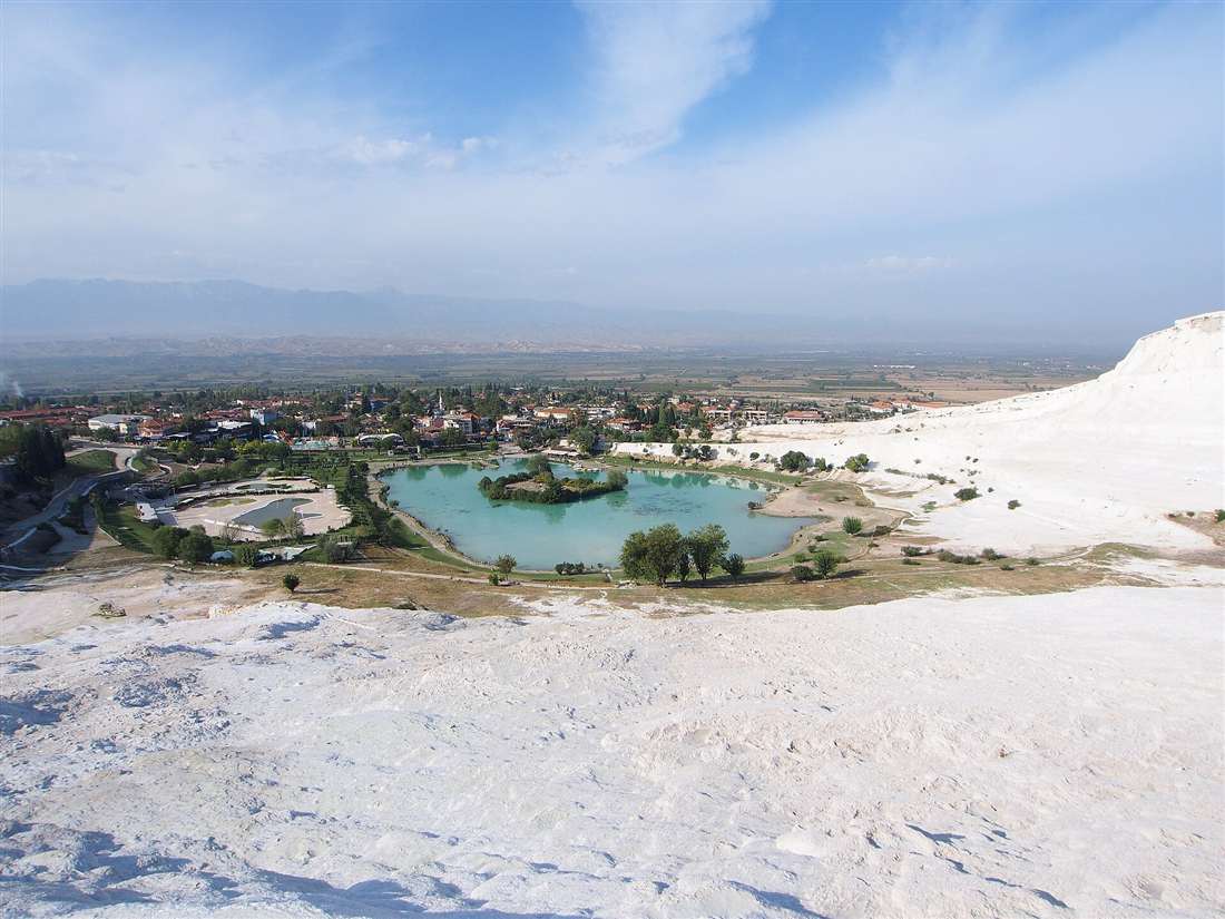 Pamukkale village and its lake seen from the white travertine terraces