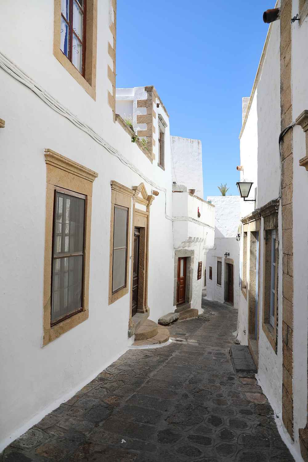 A sunlit whitewashed lane climbing through Chora, Patmos