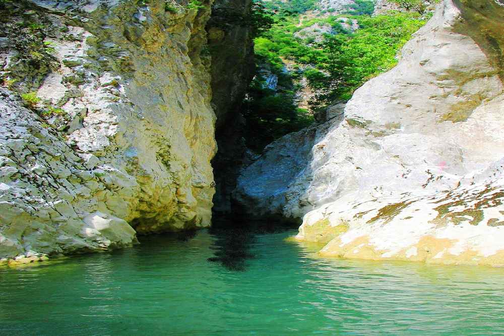 The narrows of the Acheron canyon where the cliffs close over deep green water, the stretch the myth calls the gate to the underworld