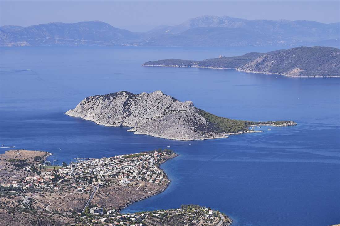 The village of Perdika and its marina with yachts and the wooded Moni islet off Aegina in the Saronic Gulf, a base for an Aegina yacht charter