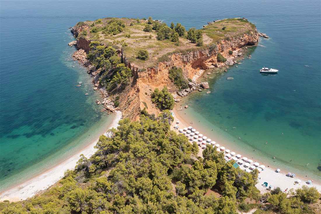 Aerial view of Kokkinokastro on Alonissos, red cliffs and pine forest between two turquoise bays