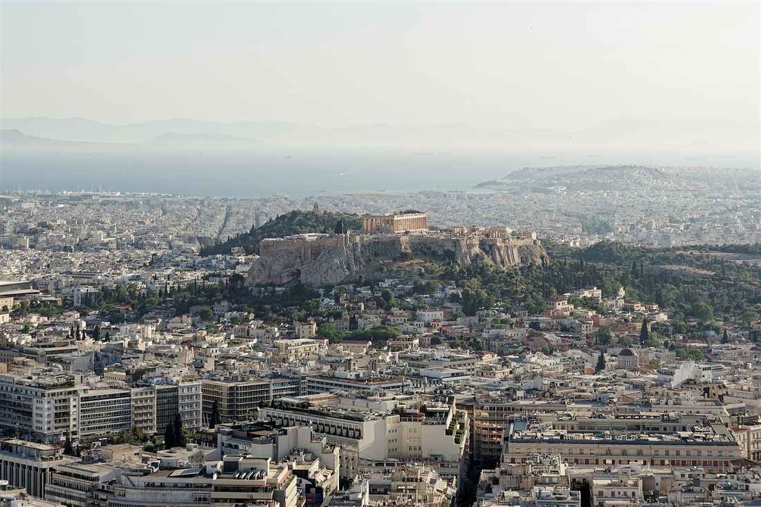 Athens spread below with the Acropolis and the Parthenon on the rock and the Saronic Gulf beyond, the view an Athens helicopter tour delivers