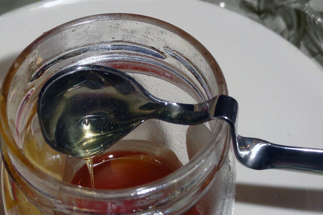 Athens honey tasting: Greek honey dripping from a spoon into a glass jar