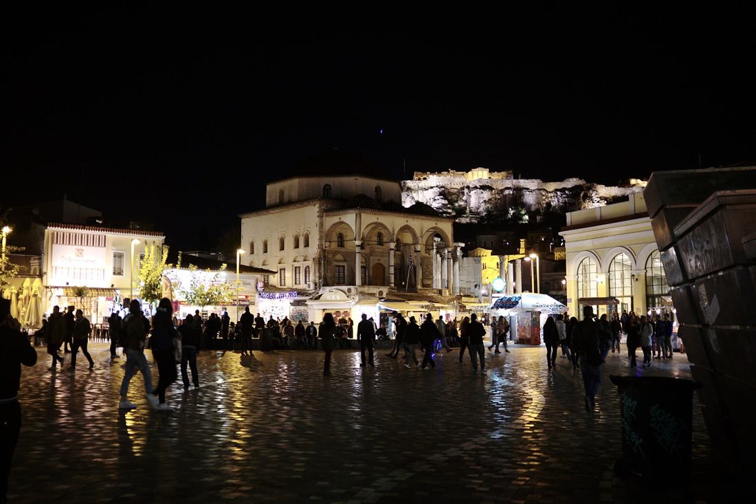 Athens pub crawl: Monastiraki Square at night with the lit Acropolis above the crowds