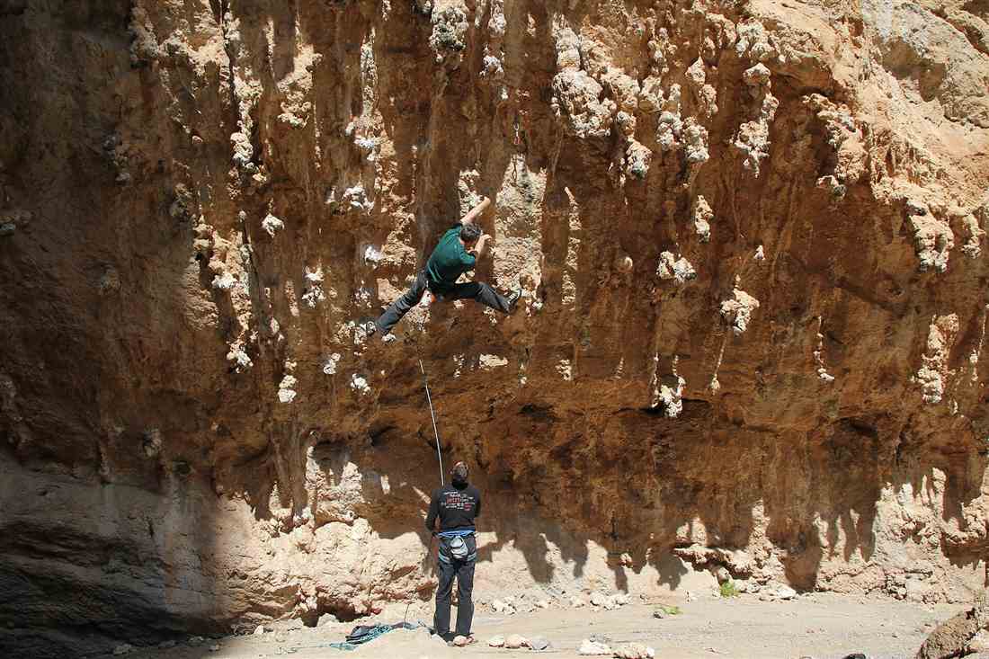 Athens rock climbing: a climber on an orange limestone overhang with a belayer below