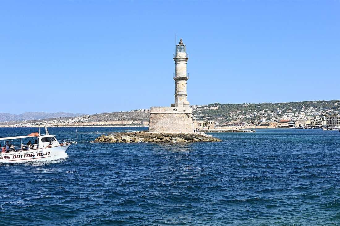 Chania catamaran cruise boat leaving the old port past the Egyptian lighthouse