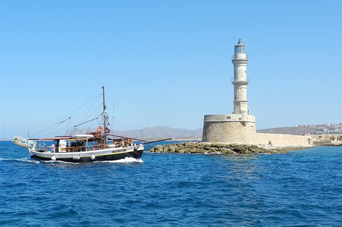 Chania sunset cruise boat sailing past the Venetian lighthouse of Chania Old Harbour