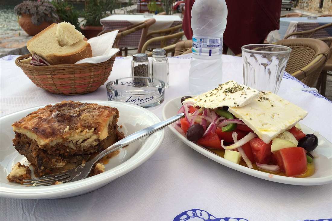 Moussaka and a Greek salad with feta served at a seaside taverna table, the sit-down course on a Corfu food tour