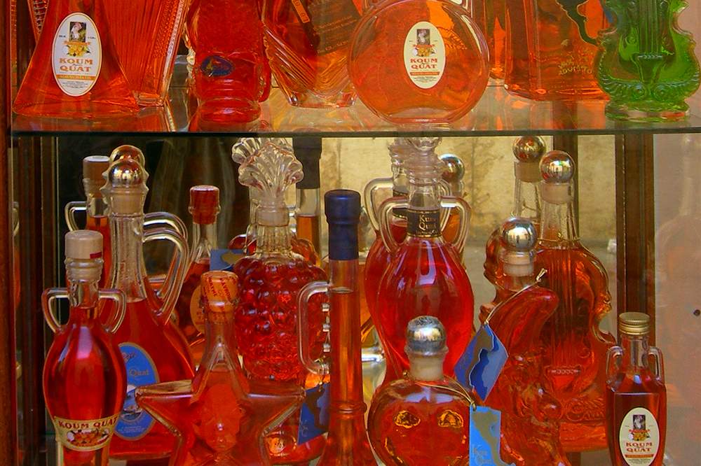 Bottles of Corfu kumquat liqueur in a shop window, the island spirit tasted on the walk