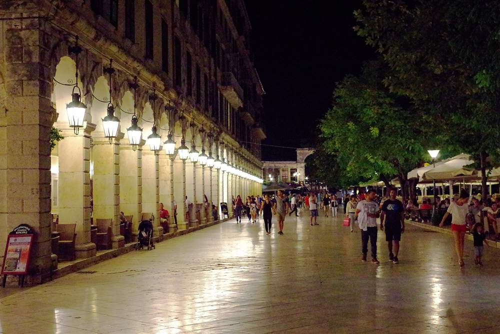 The Liston arcade in Corfu Town lit at night with evening walkers on the paving