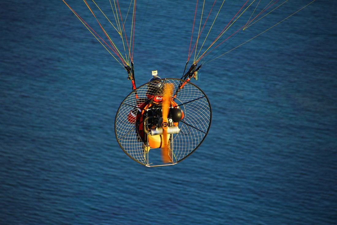 Corfu paragliding: a paramotor pilot flying under the wing lines above the blue Greek sea
