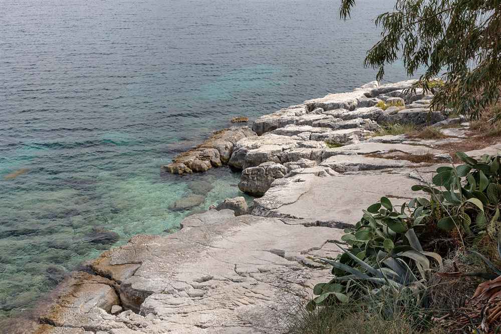 Flat limestone shelves and clear green water on the Kassiopi shore in the north-east of Corfu