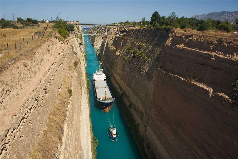 A ship under tow passing through the Corinth Canal between its vertical walls
