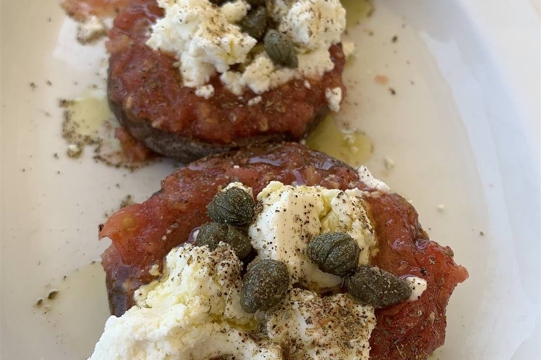 A plate of dakos, the Cretan barley rusk topped with grated tomato, mizithra cheese, capers and olive oil, tasted on a Crete food tour