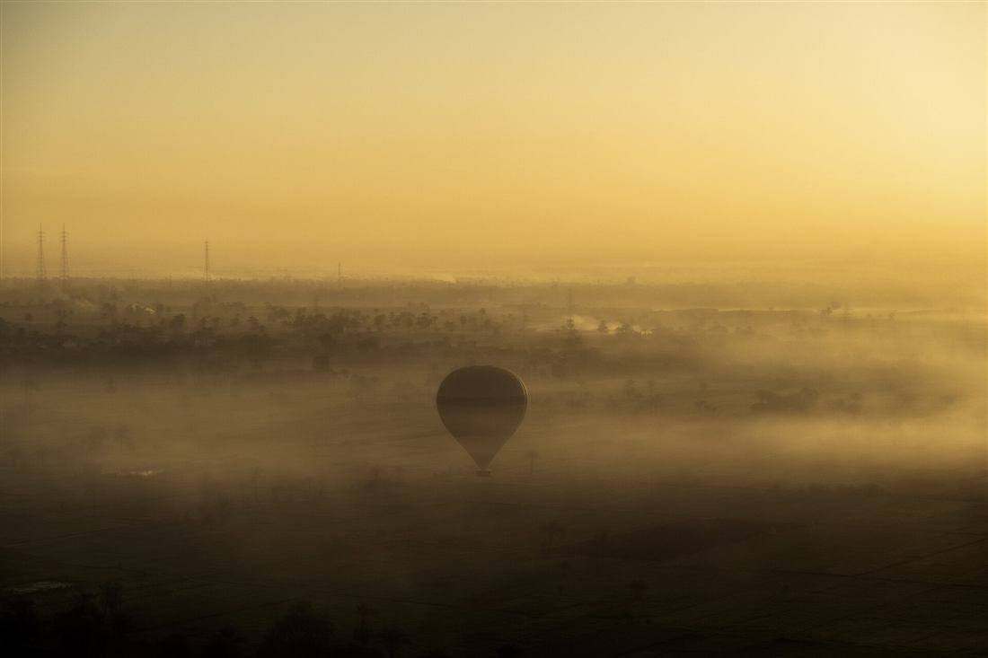 A hot air balloon drifting low through mist at sunrise, the dawn flight a Crete hot air balloon trip is built around