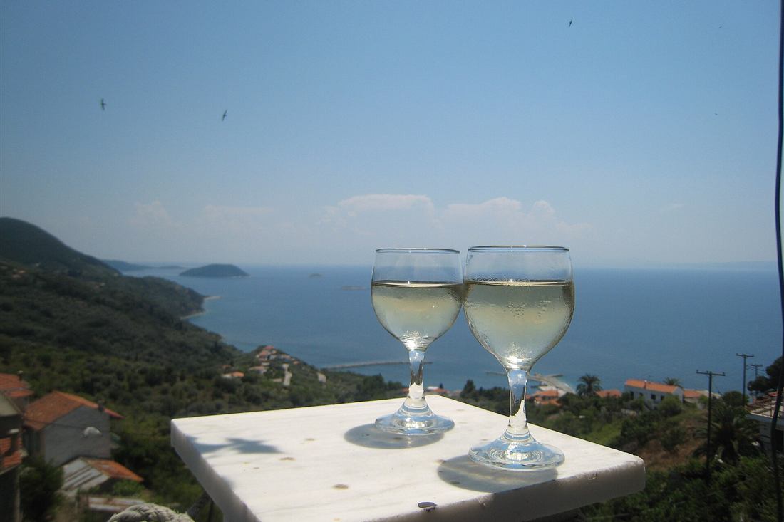 Two glasses of chilled Greek white wine on a marble table above an Aegean bay