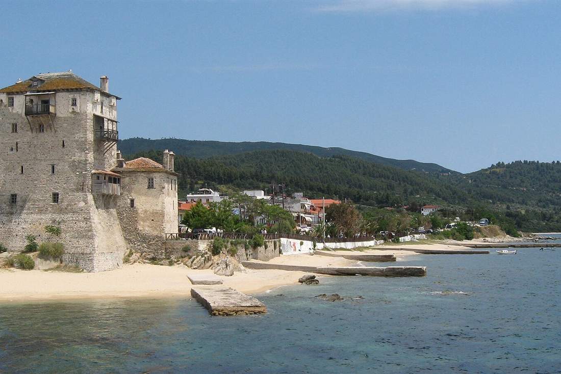 The Byzantine tower on the Ouranoupoli waterfront with boats moored beside it, the departure point for Halkidiki boat tours