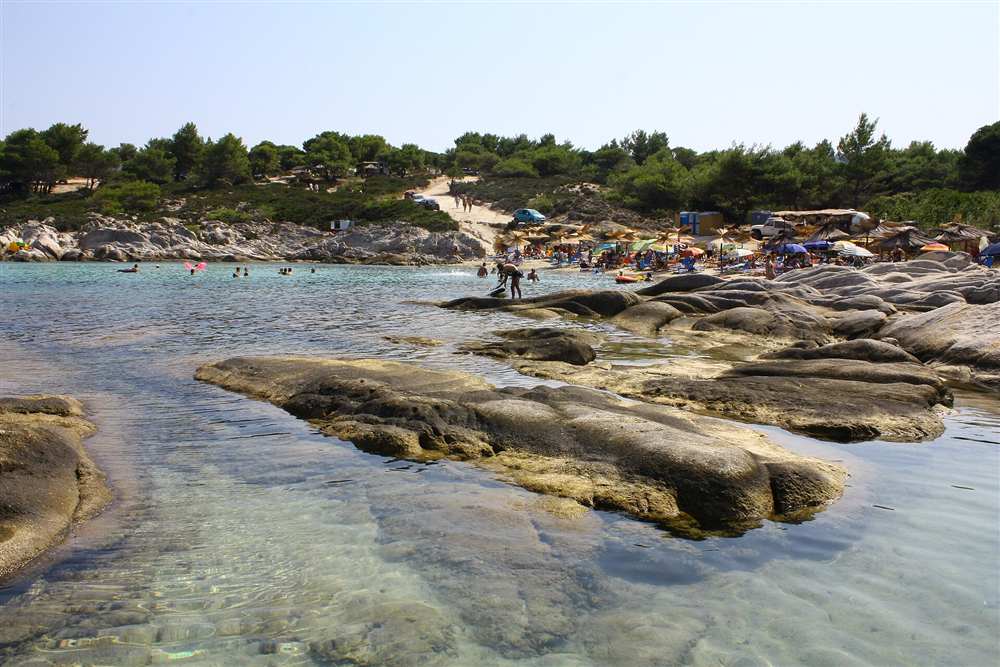 The clear shallow water and smooth rocks of the Kavourotrypes coves on Sithonia