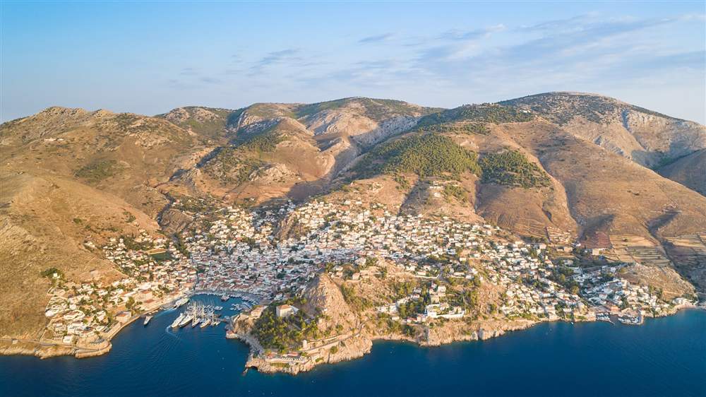 An aerial view of Hydra town and its harbour in the Saronic Gulf at golden light